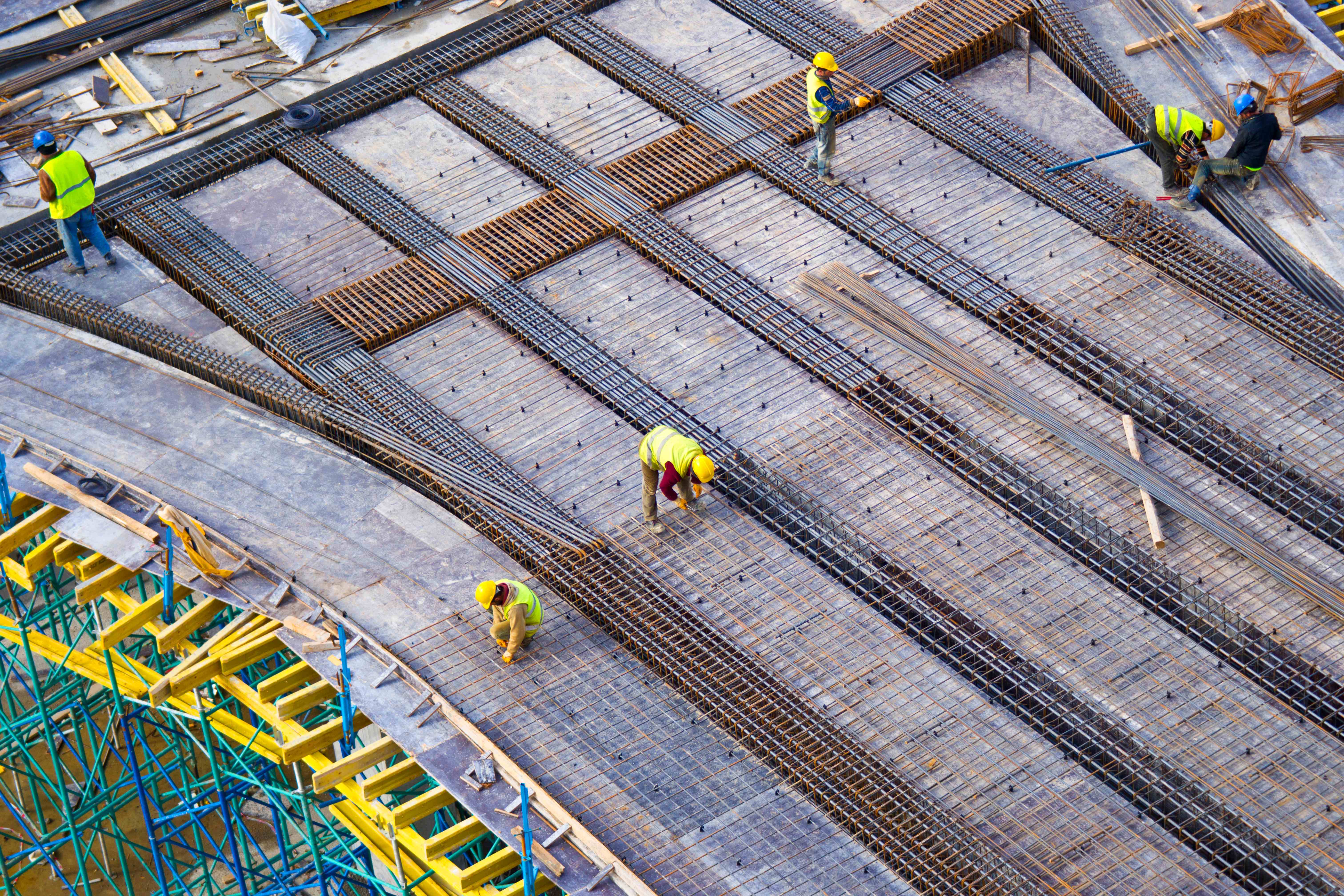 Construction workers installing rebar reinforcement on construction site from aerial view